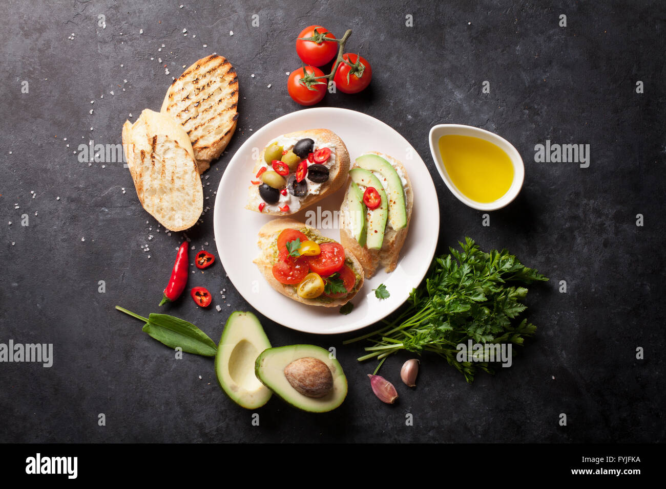 Toast-Sandwiches mit Avocado, Tomaten und Oliven auf Stein Hintergrund. Ansicht von oben Stockfoto