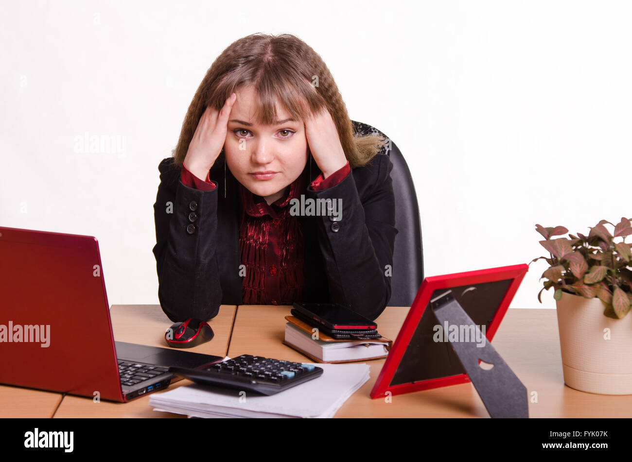Das Mädchen hinter dem Büroschreibtisch Kopf mit Händen haltend Stockfoto