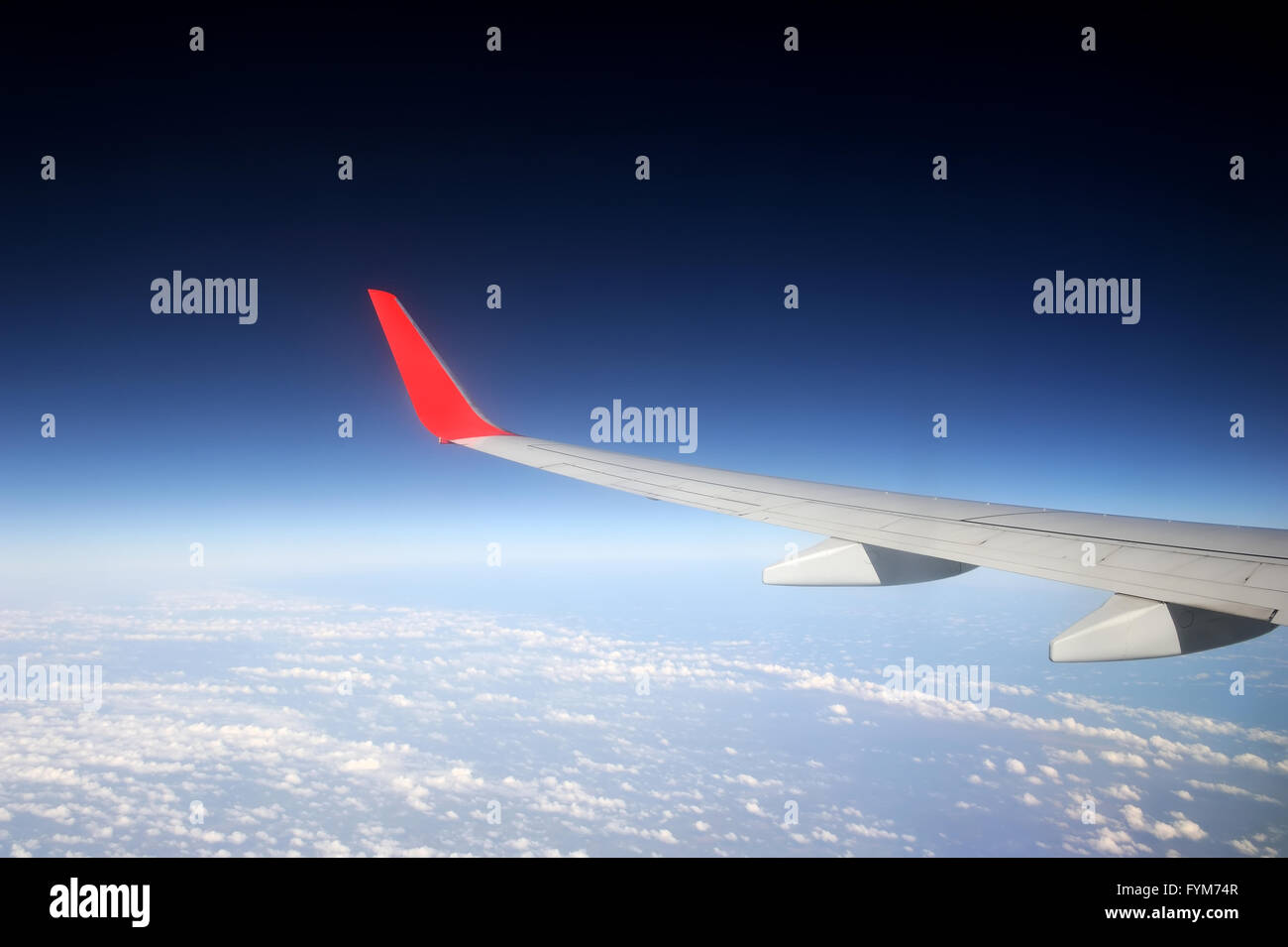 Blick aus dem Flugzeugfenster mit blauem Himmel und weißen Wolken Stockfoto