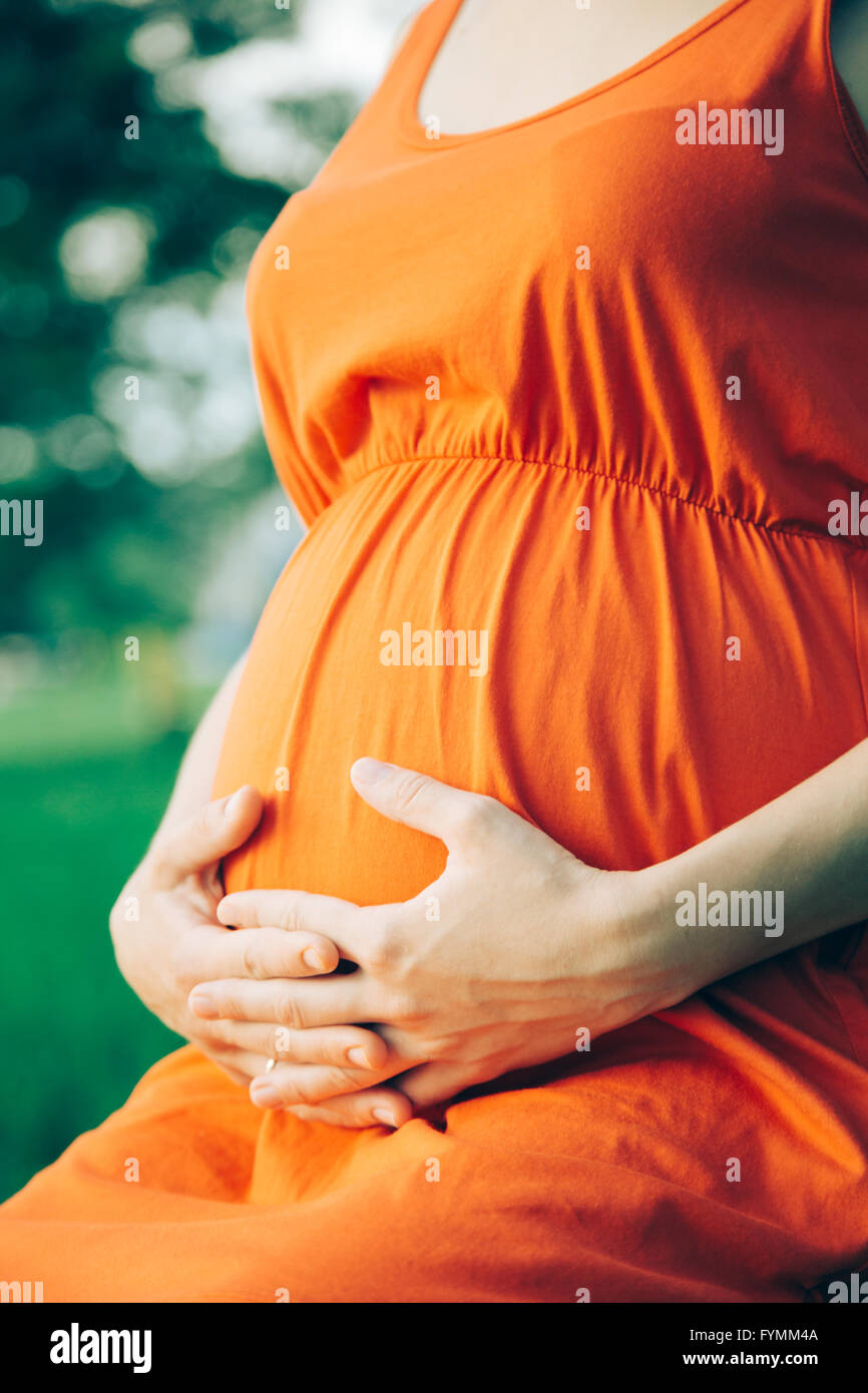 Schwangere Frau legte ihre Hände auf den Bauch Stockfoto