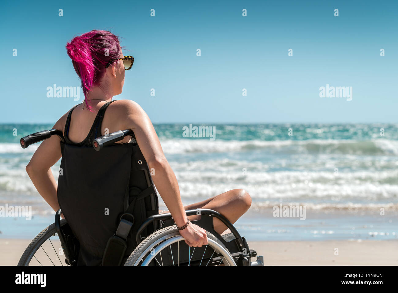 Behinderte Frau im Rollstuhl am Strand Stockfoto