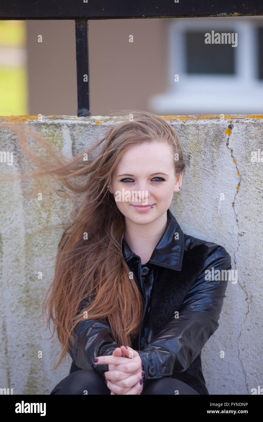 Eine Frau mit langen Wind geblasen rotes Haar draußen zu sitzen. Stockfoto