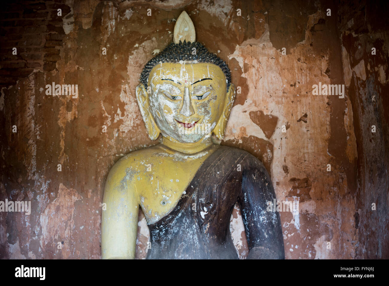 Payathonzu Tempel Buddha Statue Bagan Myanmar // BAGAN, Myanmar — Eine verwitterte Buddha Statue mit verblasster Farbe befindet sich in einem der drei miteinander verbundenen Tempel des Payathonzu Tempelkomplexes in Bagan. Der Payathonzu (auch bekannt als Paya-thone-zu), wörtlich „Tempel der drei Buddhas“, wurde im späten 13. Jahrhundert erbaut und stellt das einzige bekannte Beispiel für drei miteinander verbundene Schreine in Bagans archäologischer Zone dar. Der Komplex enthält außergewöhnliche Wandmalereien, die von Wissenschaftlern als letzte Beispiele heidnischer Maltraditionen betrachtet werden, obwohl die Konstruktion mysteriös ab war Stockfoto
