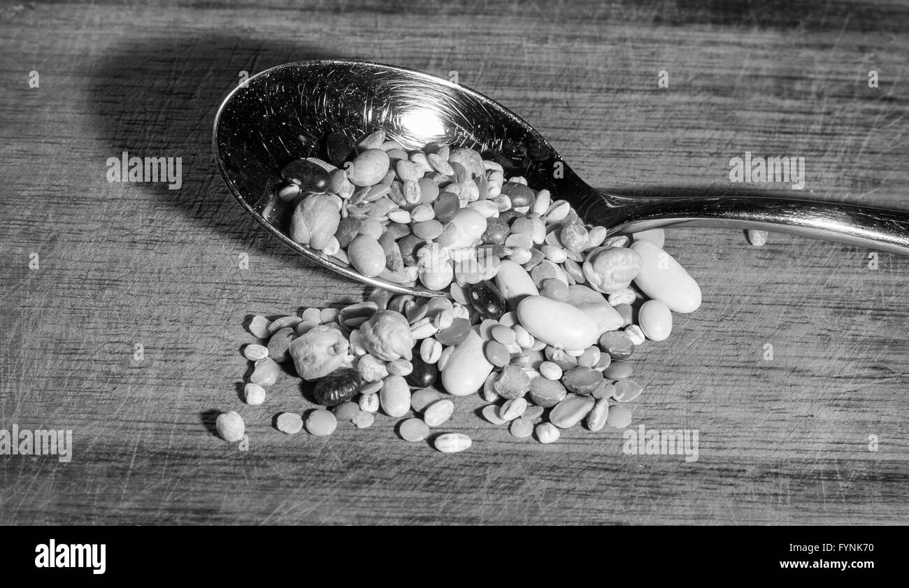 jede Art von Hülsenfrüchten in einem Löffel auf ein Schneidbrett aus Holz Stockfoto