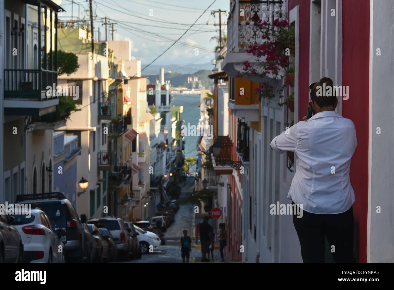 San Juan, Puerto Rico-Frau am Telefon suchen eine bunte Straße am Meer entlang Stockfoto