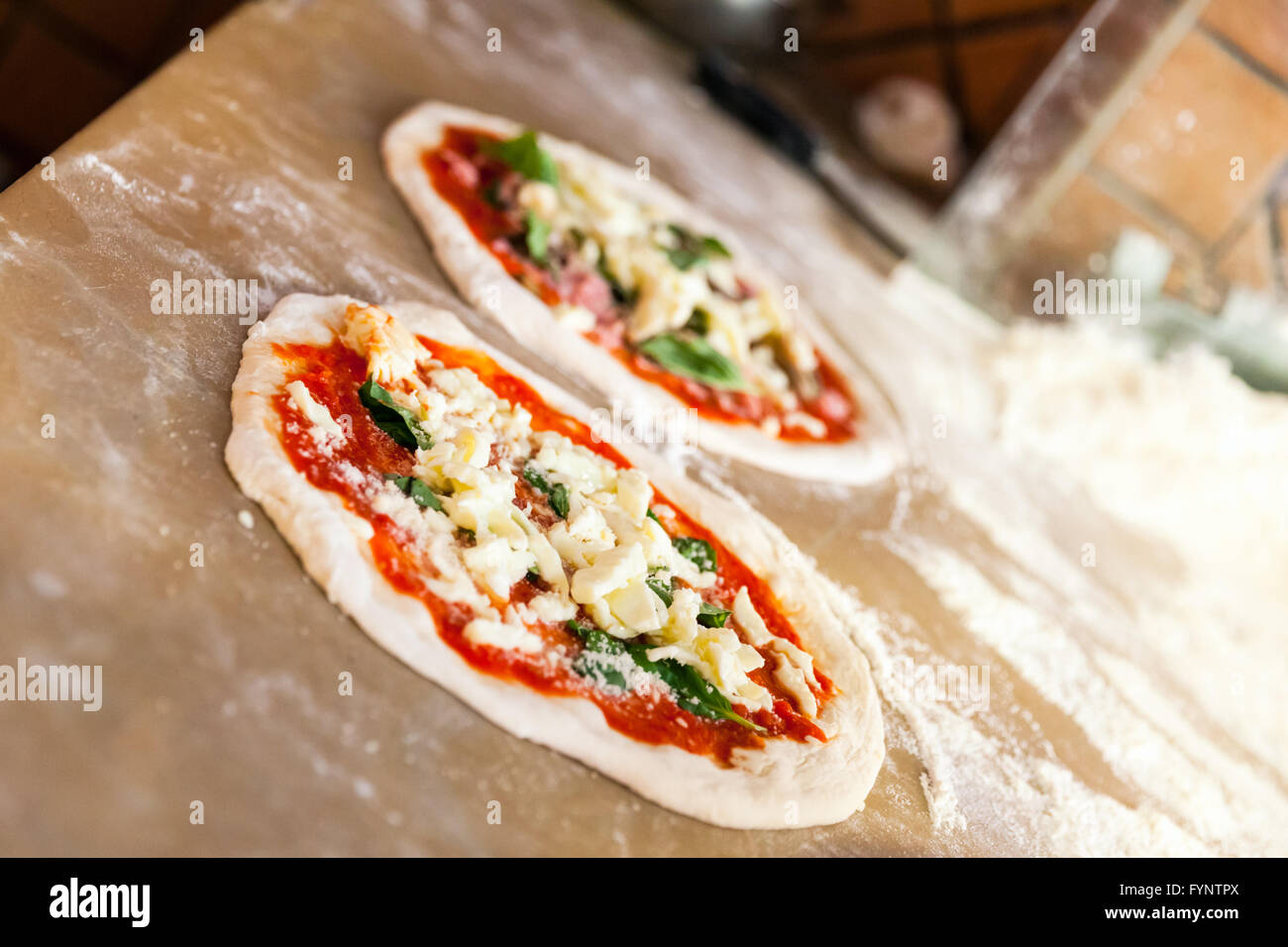 Pizza Margherita vorbereiten, sind zwei Teile fertig zum Backen. Selektiven Fokus Stockfoto