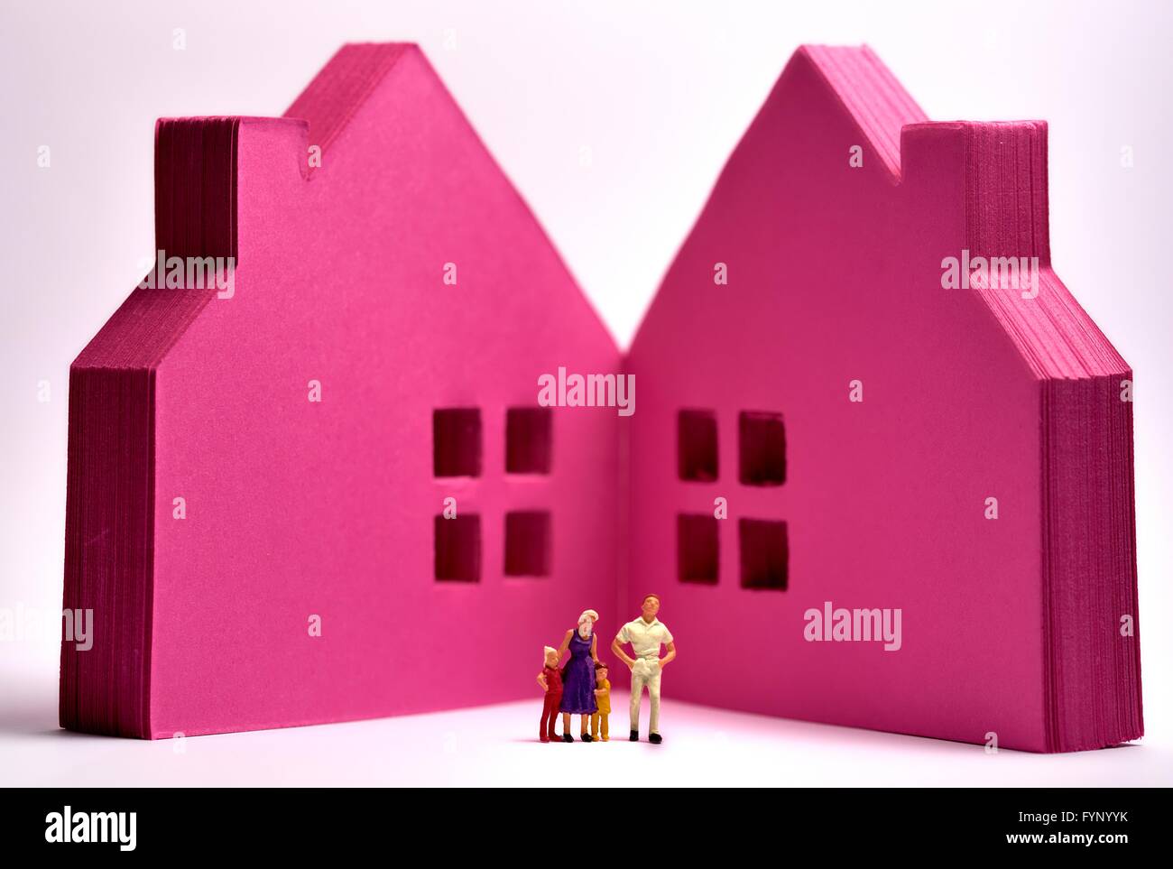 Rosa Papierblock in Form von Häusern mit einer Miniatur-Figurenfamilie, die davor steht Stockfoto