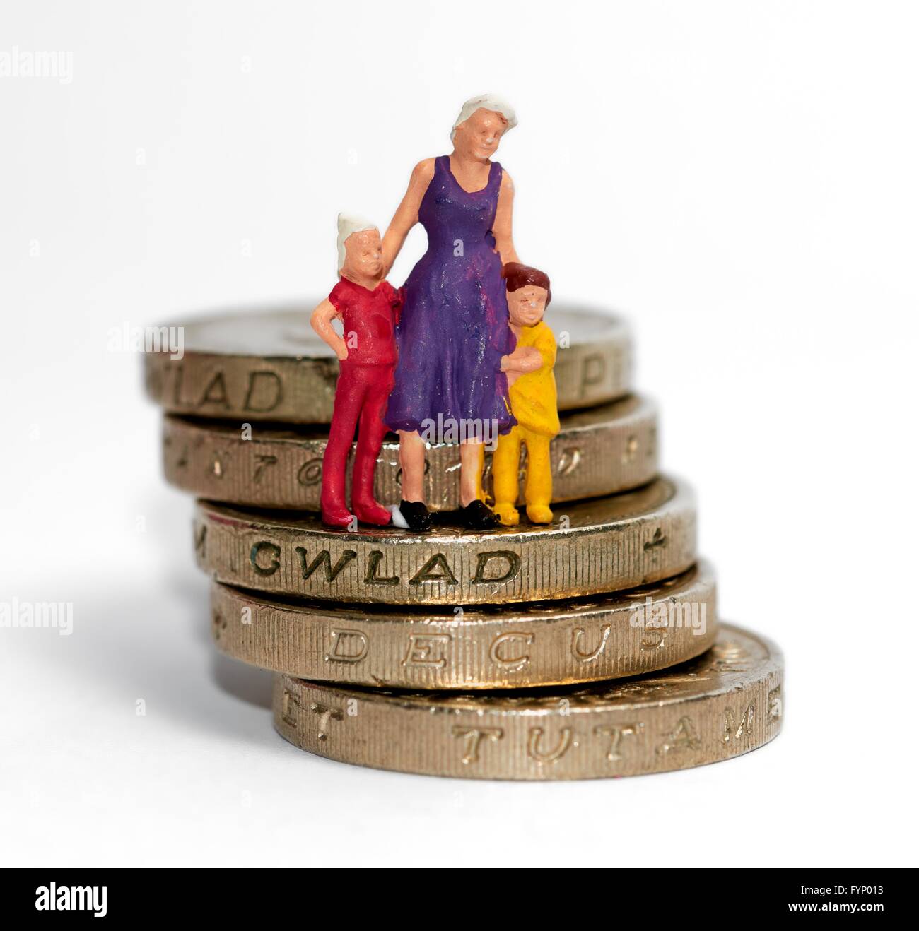 Eine Miniatur Figur Frau mit 2 Kindern, stehend auf einem Stapel von 1 Pfund-Münzen Stockfoto