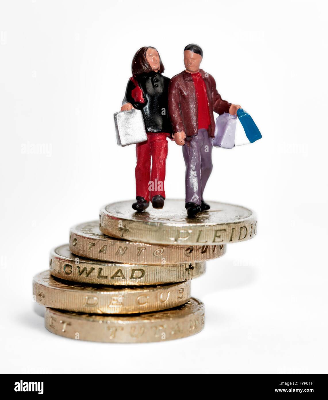 Ein Miniatur-paar Einkaufstaschen Stand am Anfang von einem Stapel von Pfund-Münzen. Stockfoto