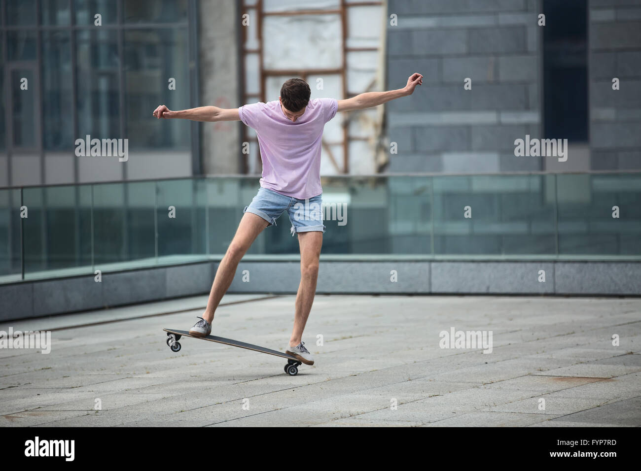 Stilvolle Teenager macht ein Longboard tricks Stockfoto