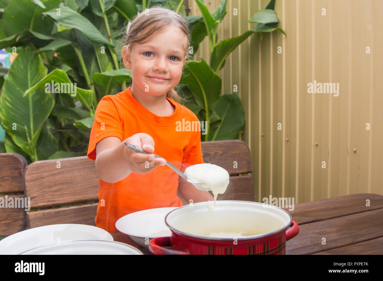 Mädchen mit einem Lächeln erlegt Grieß seinen Teller Stockfoto