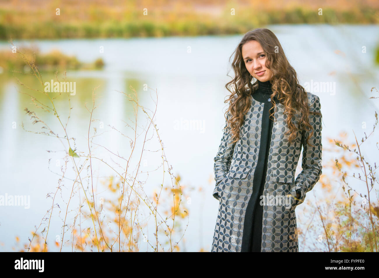 Porträt eines jungen Mädchens auf dem Hintergrund eines Sees bei Herbstwetter Stockfoto