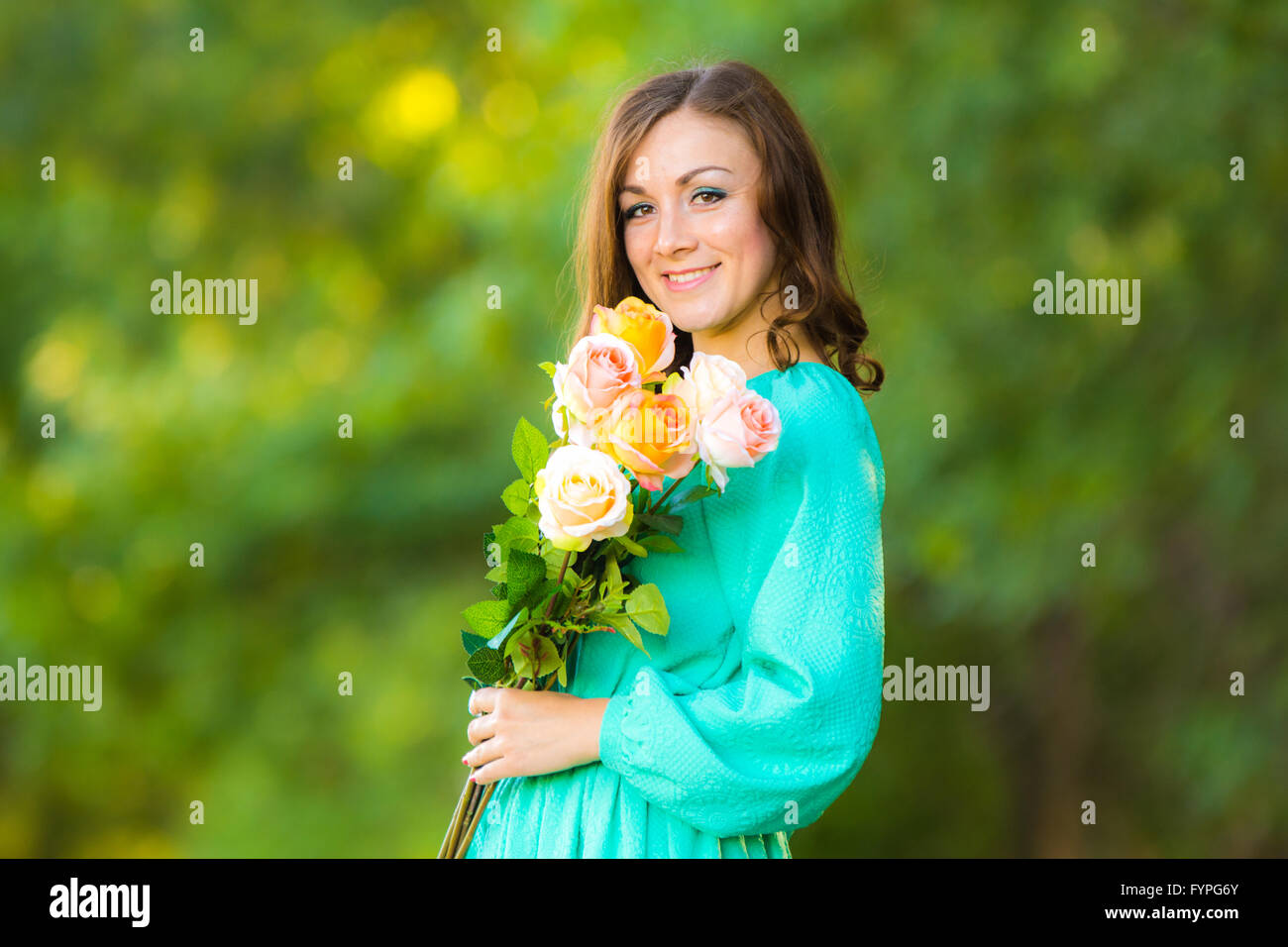 Porträt eines Mädchens mit einem Strauß Rosen auf dem Hintergrund unscharf Laub Stockfoto