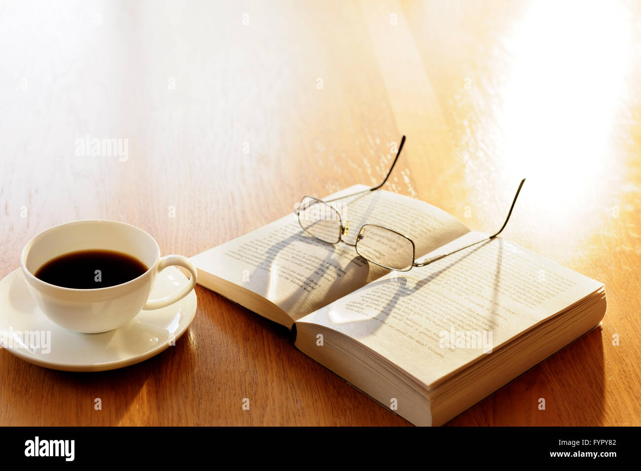 Tasse Kaffee mit einem Buch und Brille. Stockfoto