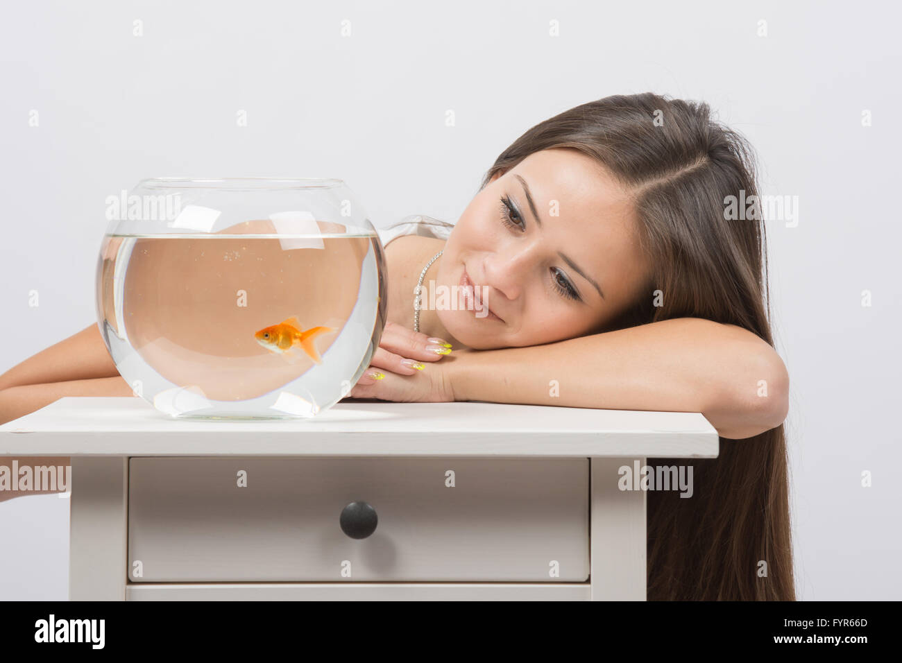 Schöne Mädchen träumt und sieht einen Goldfisch im aquarium Stockfoto