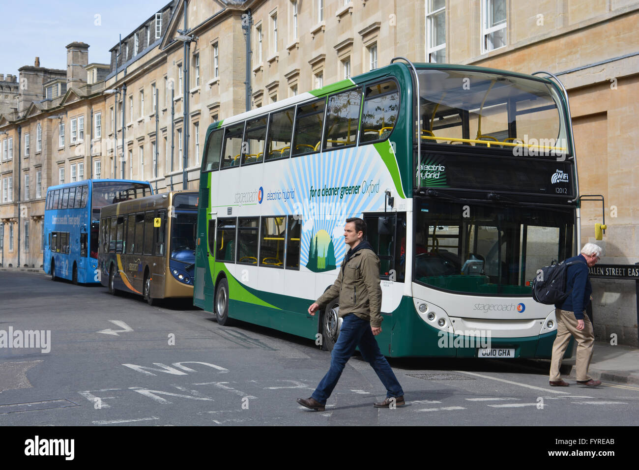 2 Männer beim Überqueren der Straße vor Stagecoach-Elektro-Hybrid-Bus in Magdalen Street East, Oxford Stadtzentrum entfernt. Stockfoto
