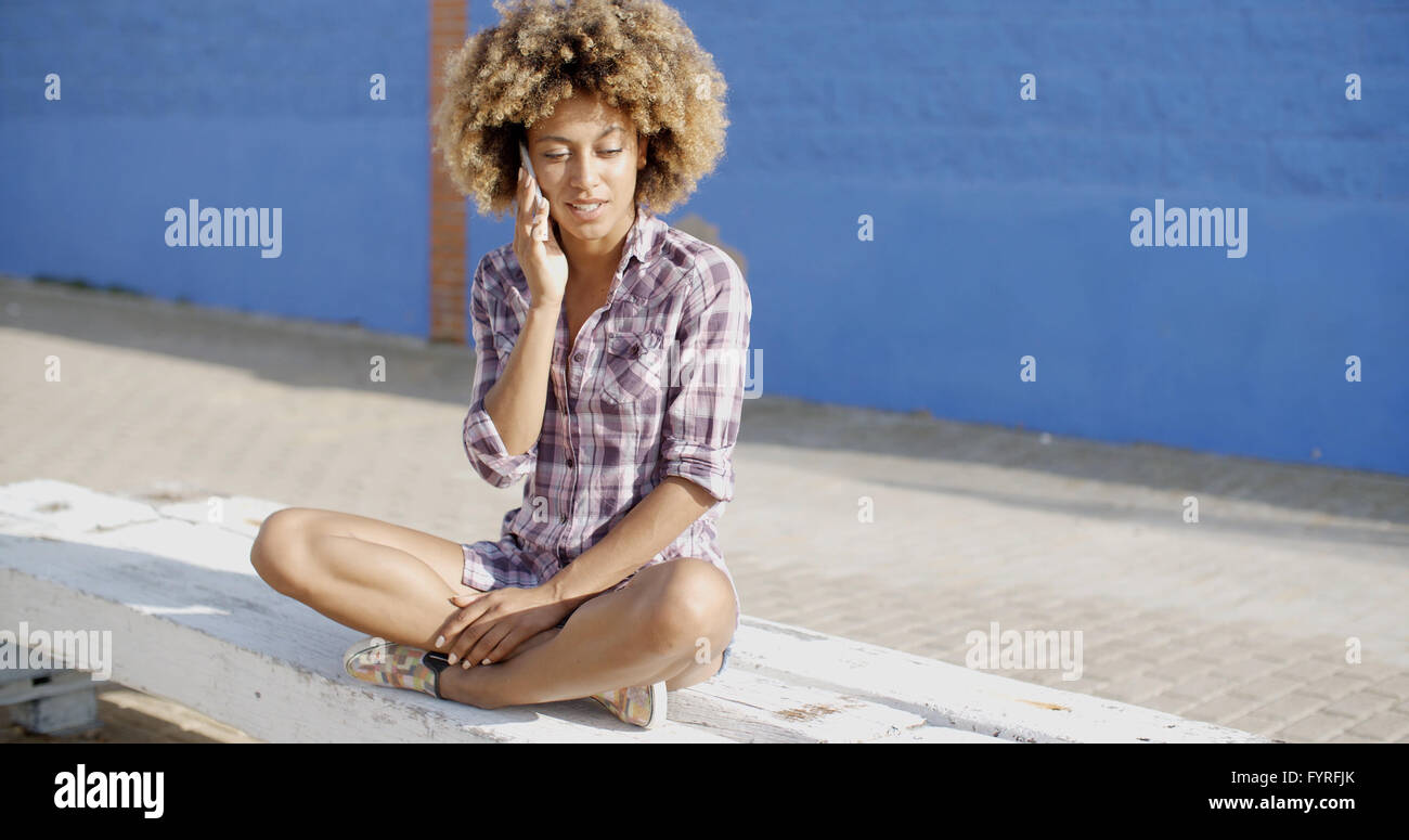 Frau mit Smartphone sitzen auf Steinmauer Stockfoto