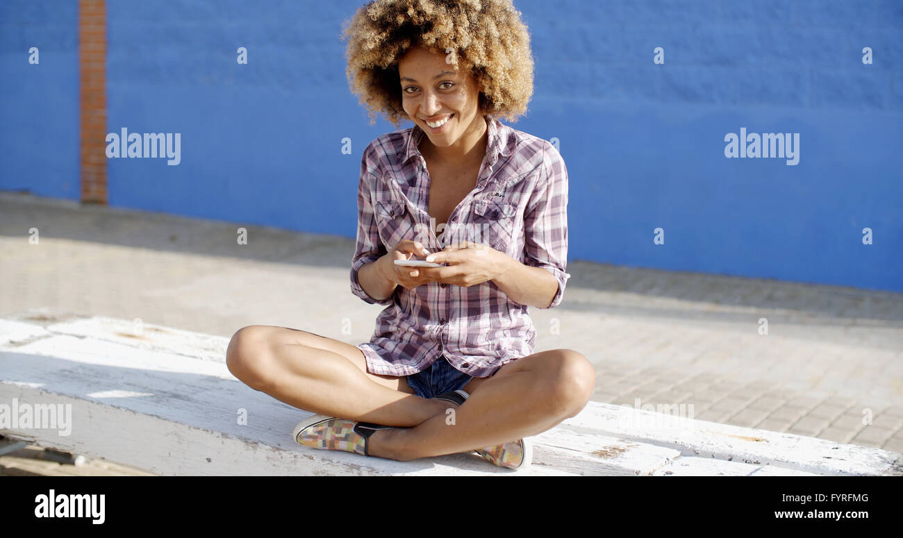 Weibchen mit Handy auf A Straße Stockfoto