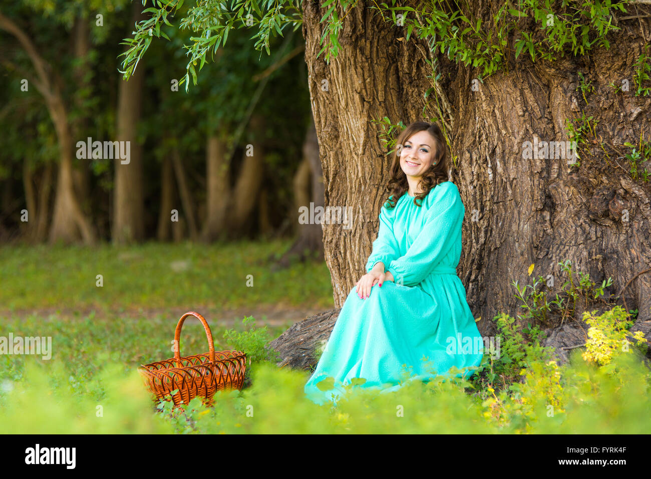 Ein Mädchen in einem langen Kleid, setzte sich an einen Baum im Wald Stockfoto