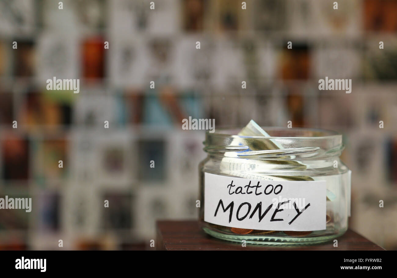 Glas Glas Witn Geld für Tattoo, unkenntlich Skizzen im Hintergrund Stockfoto