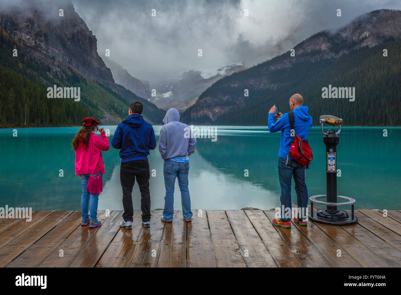 Eine Gruppe von Touristen, die den Lake Louise im Banff Nationalpark Canada während eines regnerischen Tages beobachten und fotografieren Stockfoto