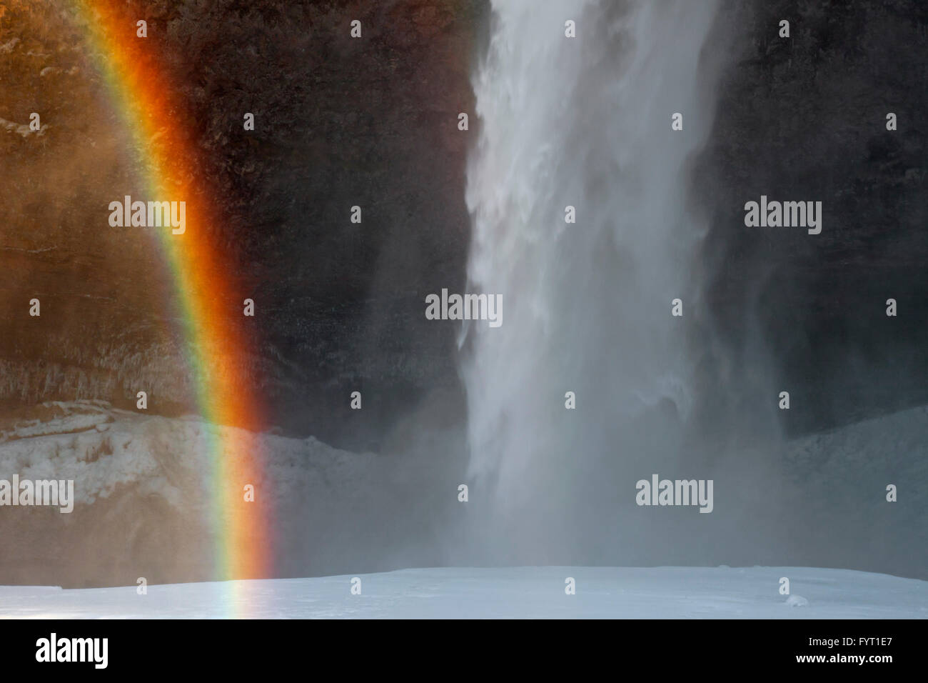 Regenbogen im Spray von Seljalandsfoss, 66 m hohe Wasserfall liegt am Fluss Seljalandsá im Winter, Rangárþing Eystra, Island Stockfoto
