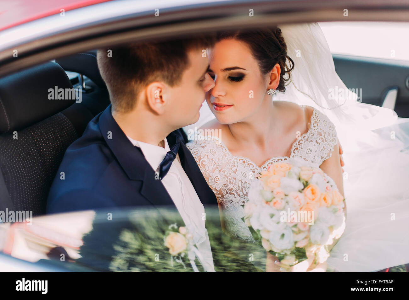 Braut und Bräutigam stehen am Fenster gehen für einen Kuss. Romantische Momente. Stockfoto