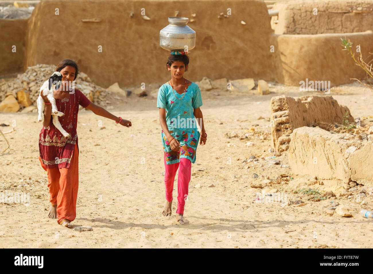 Frauen und Kinder Wasser schöpfen aus der Auslosung gut und tragen die Töpfe in ihr Dorf in der Nähe von Thar-Wüste, Jaisalmer, Indien Stockfoto