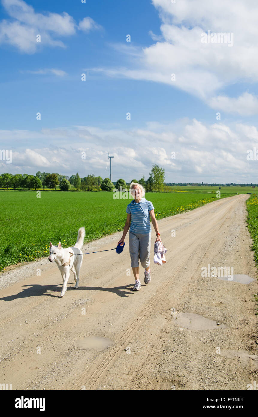Frau mit einem Hund geht auf einer Landstraße Stockfoto