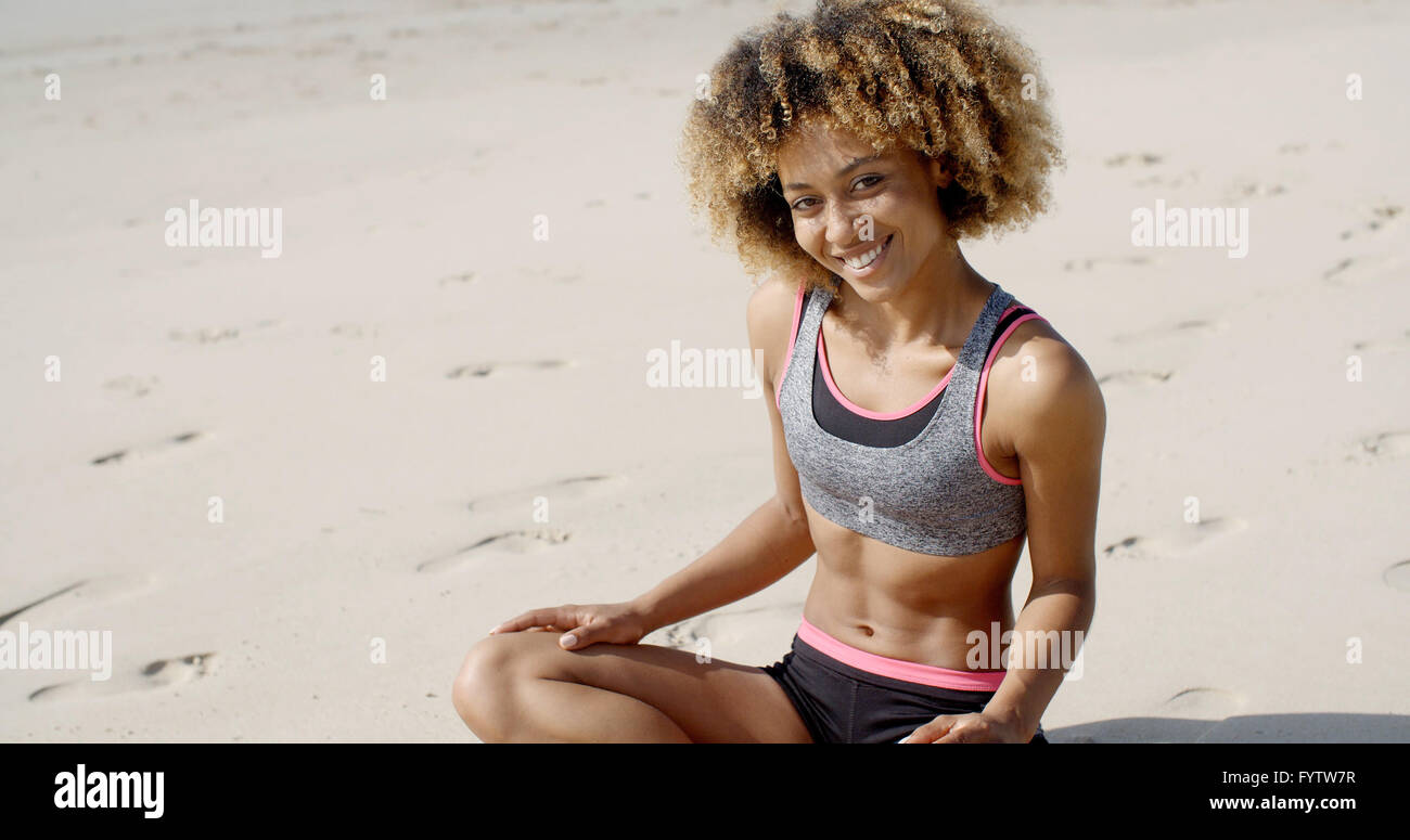 Frau im sportlichen Outfit sitzt auf dem Sand Stockfoto