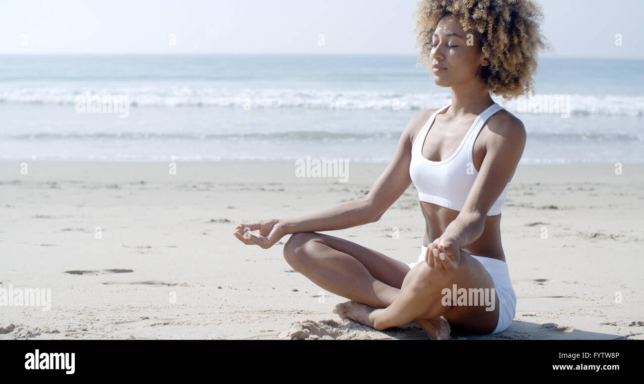 Frau am Strand im Lotussitz meditieren Stockfoto