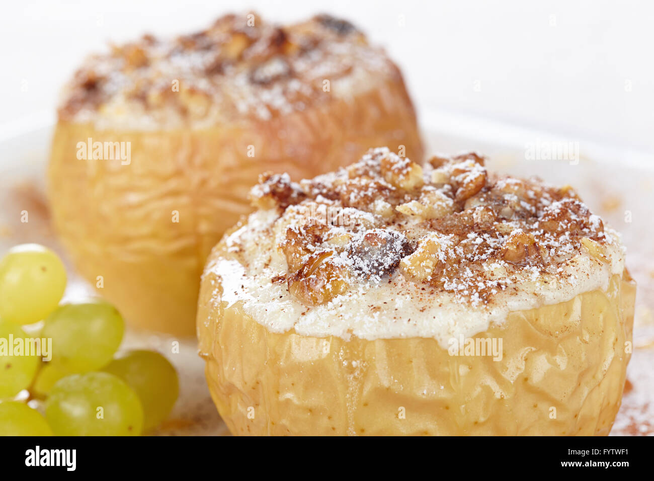 Äpfel gebacken mit Quark und Rosinen, dekoriert mit Nüssen, Zimt und Puderzucker Stockfoto