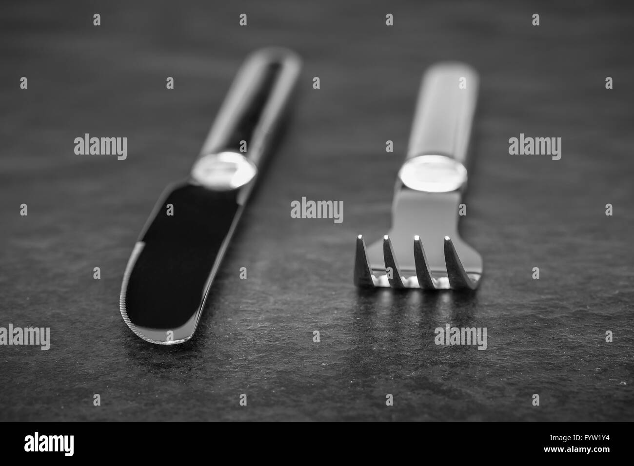Silbriges Messer und Gabel aus Metall auf einer Steinplatte Stockfoto
