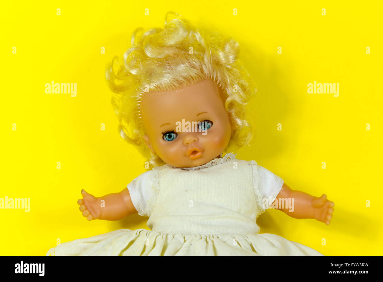 Vintage Puppe, Dolly, Marionette, altes Spielzeug, Retro, gelber Hintergrund, blaue Augen, blonde Haare, Kleinkind, infantil, kindisch Stockfoto