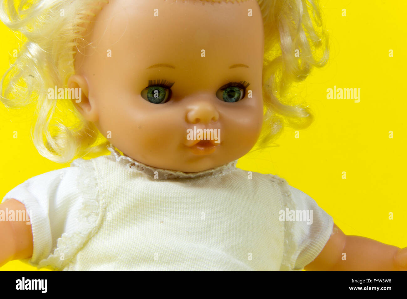 Vintage Puppe, Dolly, Marionette, altes Spielzeug, Retro, gelber Hintergrund, blaue Augen, blonde Haare, Kleinkind, infantil, kindisch Stockfoto