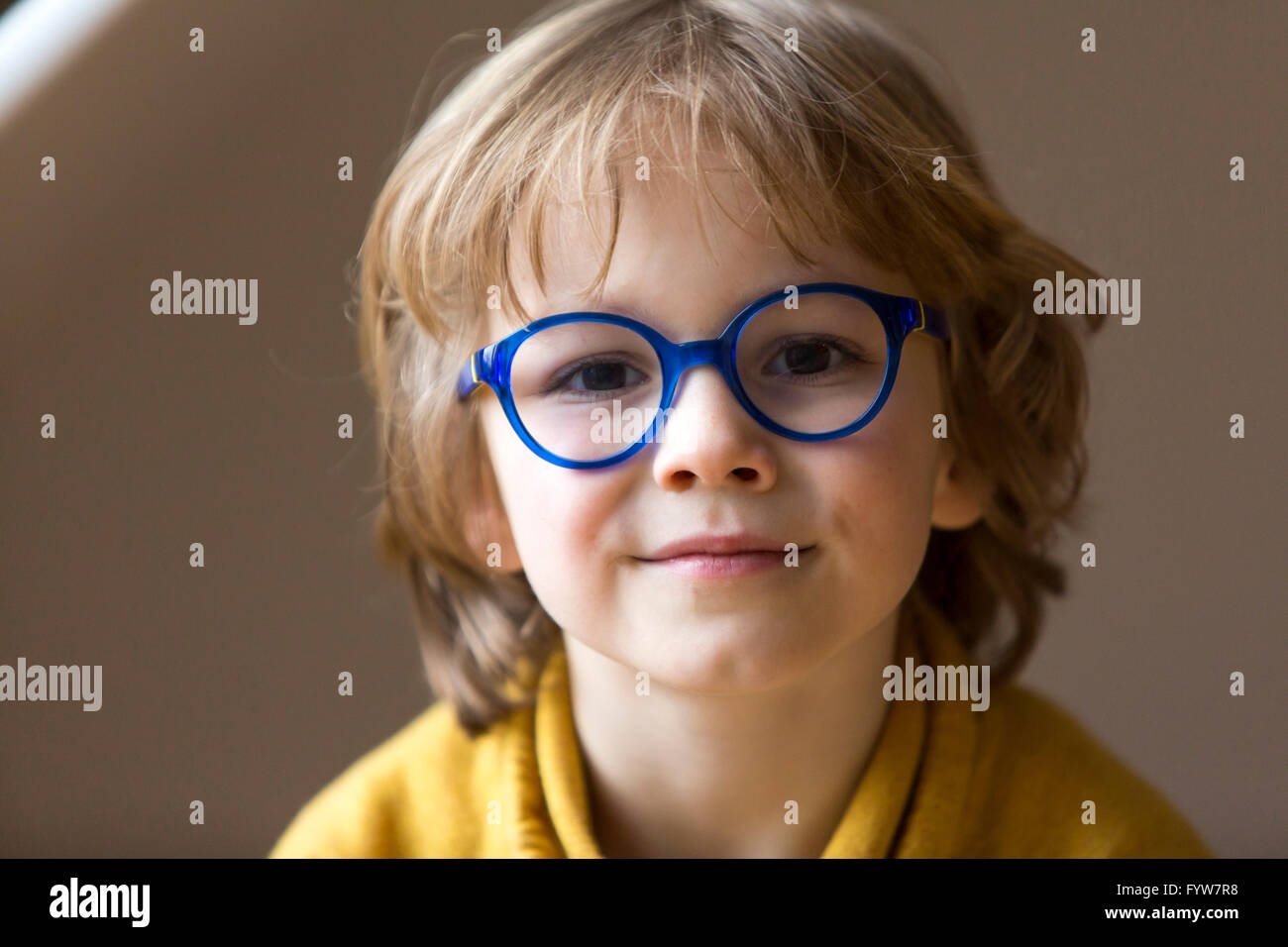 Junge, 6 Jahre alt, sieht freundlich aus, lächelt, mit Brille, mit einem blauen Rahmen, Stockfoto