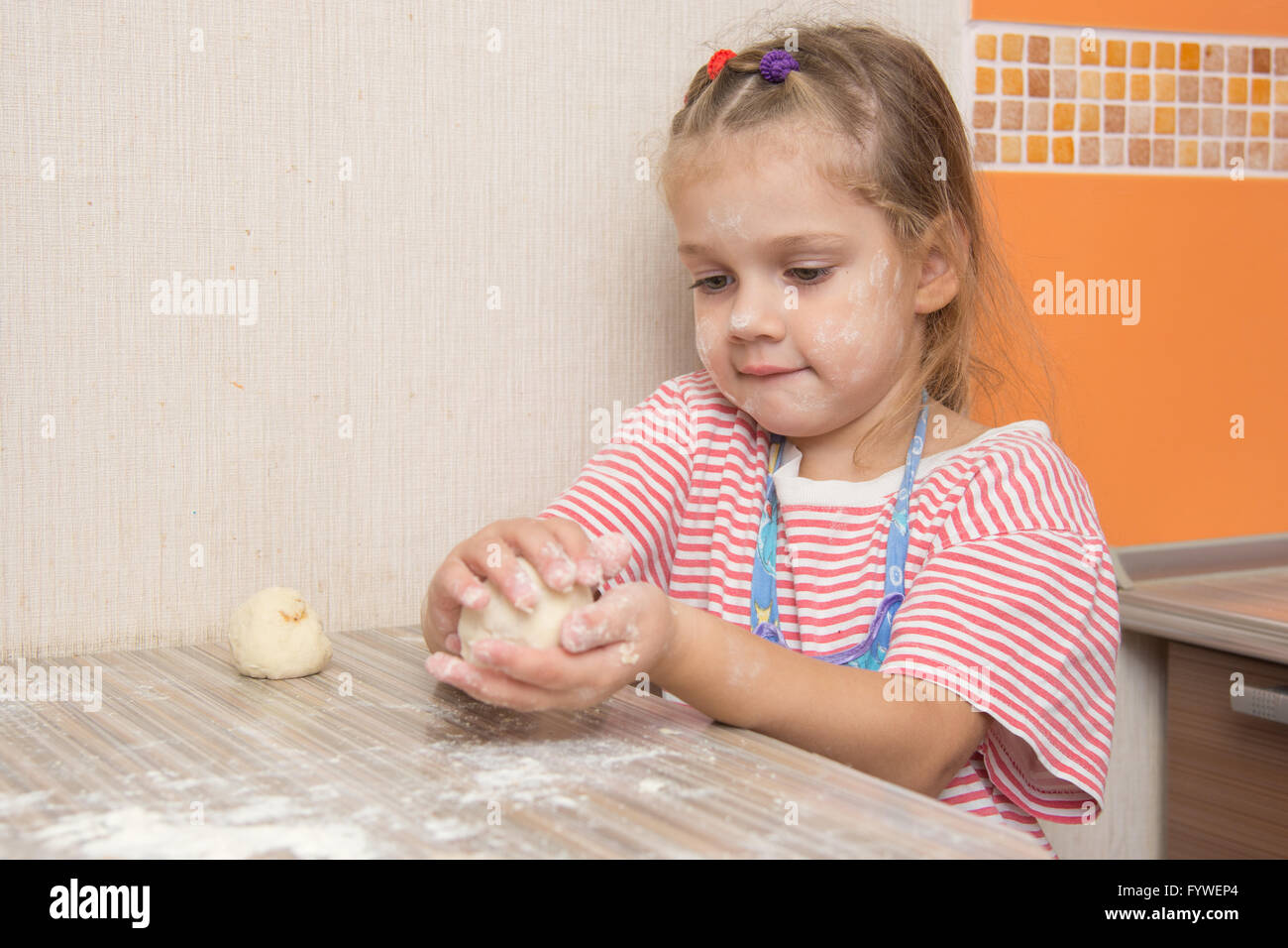 Mädchen formt eine Torte am Küchentisch Stockfoto