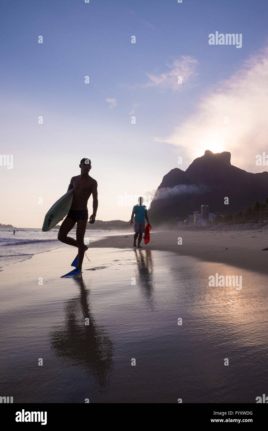 RIO DE JANEIRO - 8. März 2016: Bodyboarder Fuß am Strand von São Conrado unter einem Sonnenuntergang Silhouette des legendären Pedra da Gávea. Stockfoto