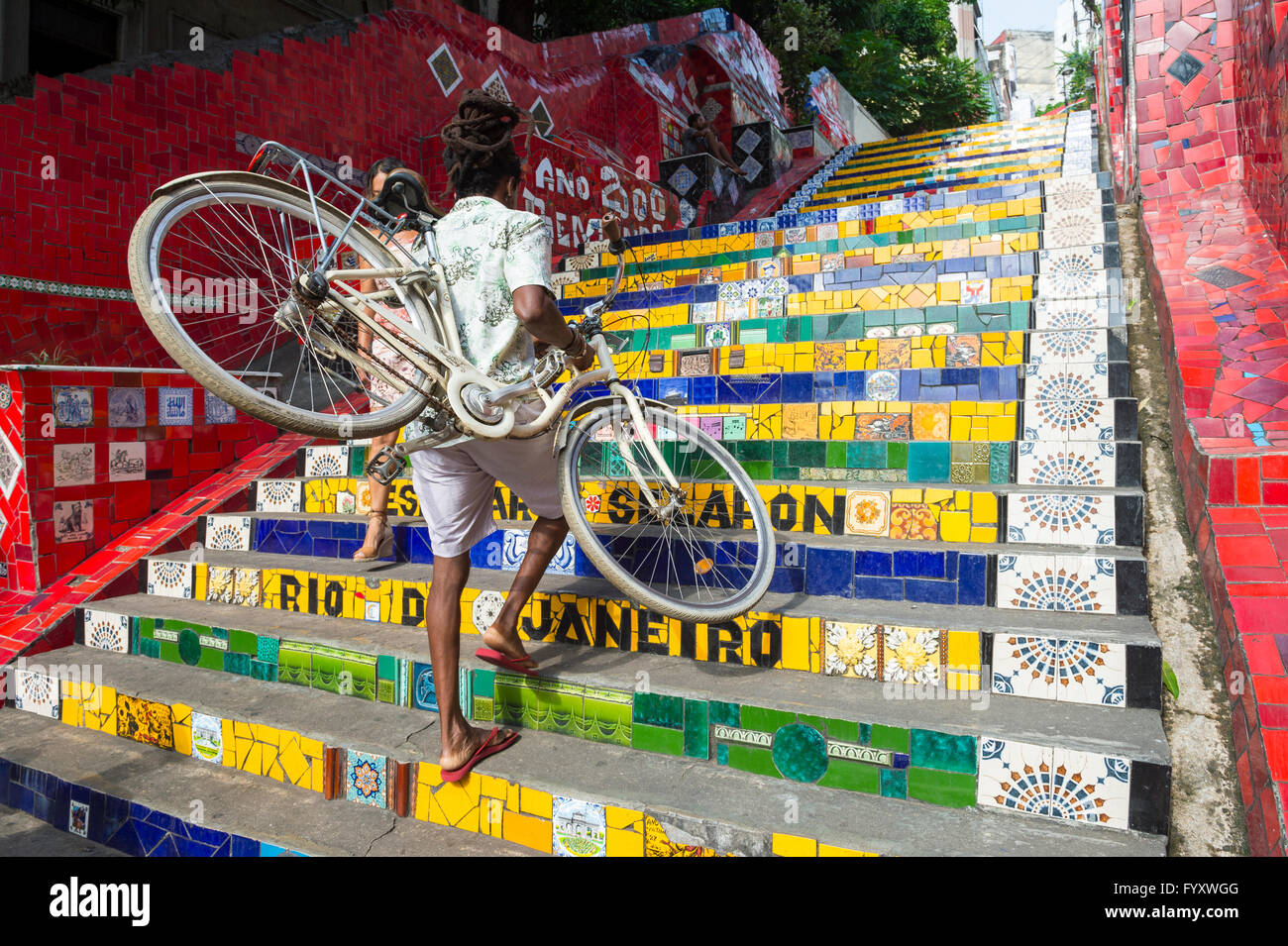 RIO DE JANEIRO - 29. März 2016: Ein Radfahrer geht sein Fahrrad, das bunte Mosaik-Fliesen an den Selaron-Stufen. Stockfoto