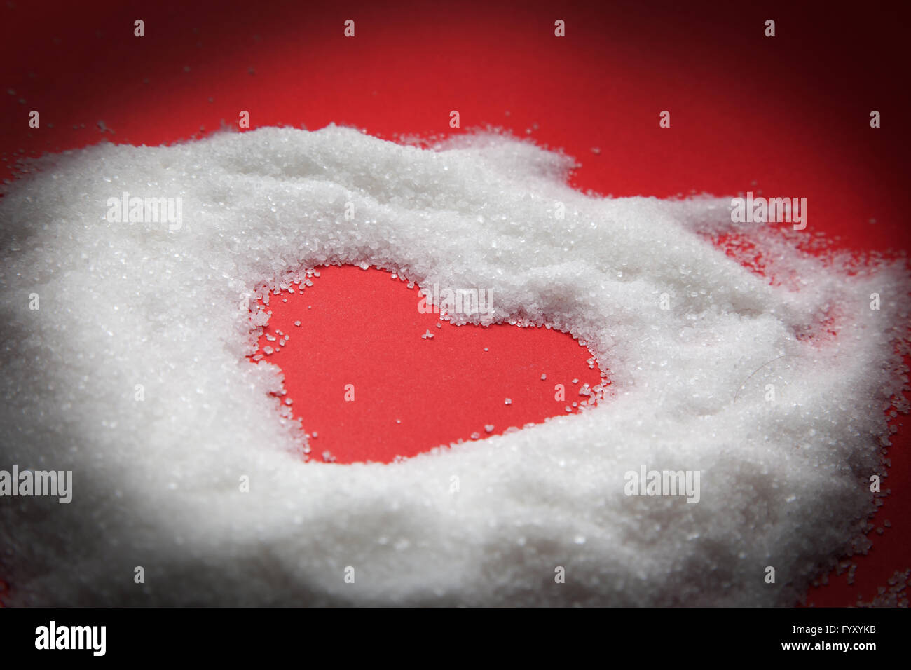 Herzform in Zucker auf rotem Grund. Stockfoto