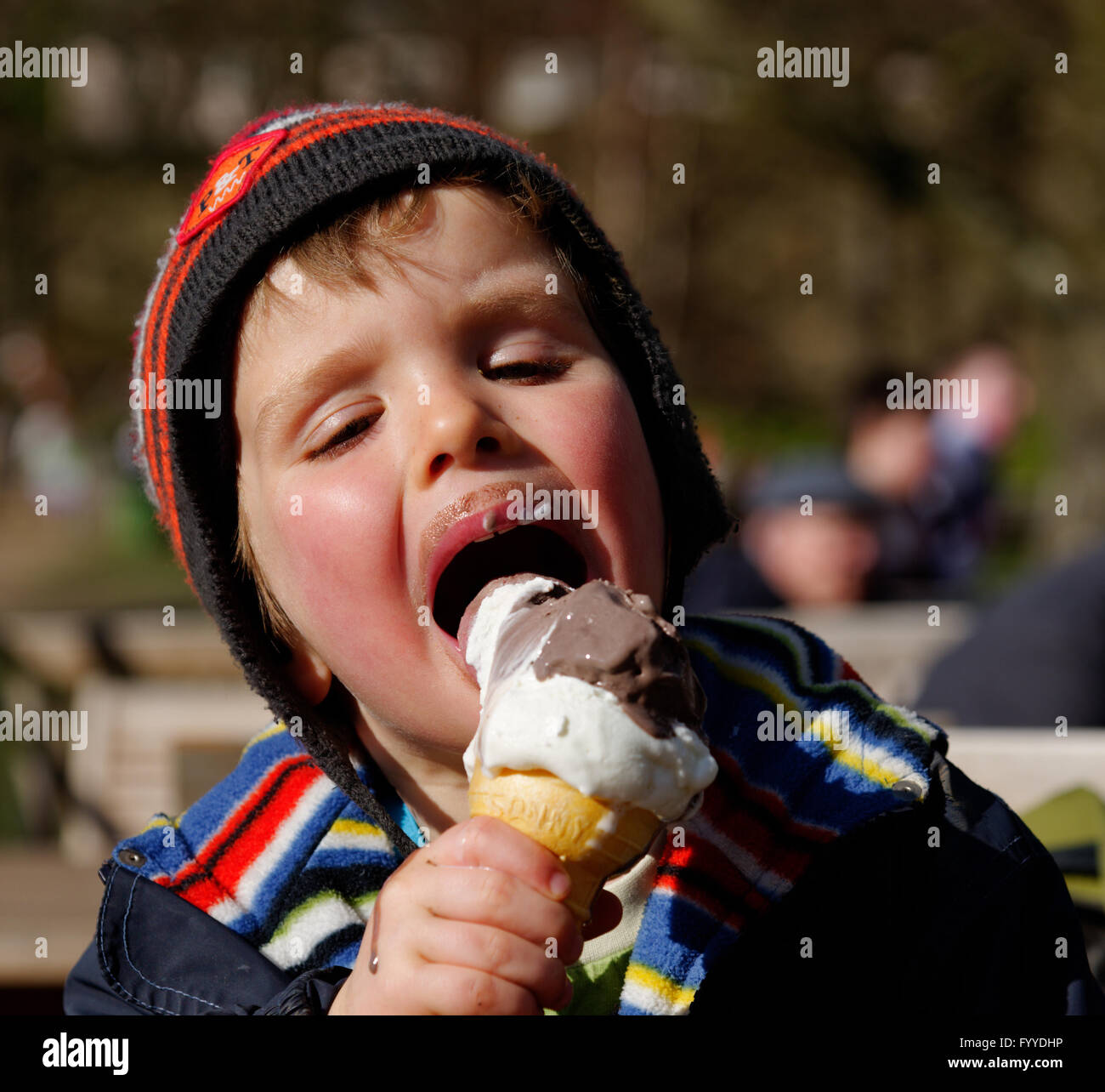 Ein vier Jahre alter Junge, Essen ein Eis - im Frühling, so hat er noch einen Hut auf. Stockfoto