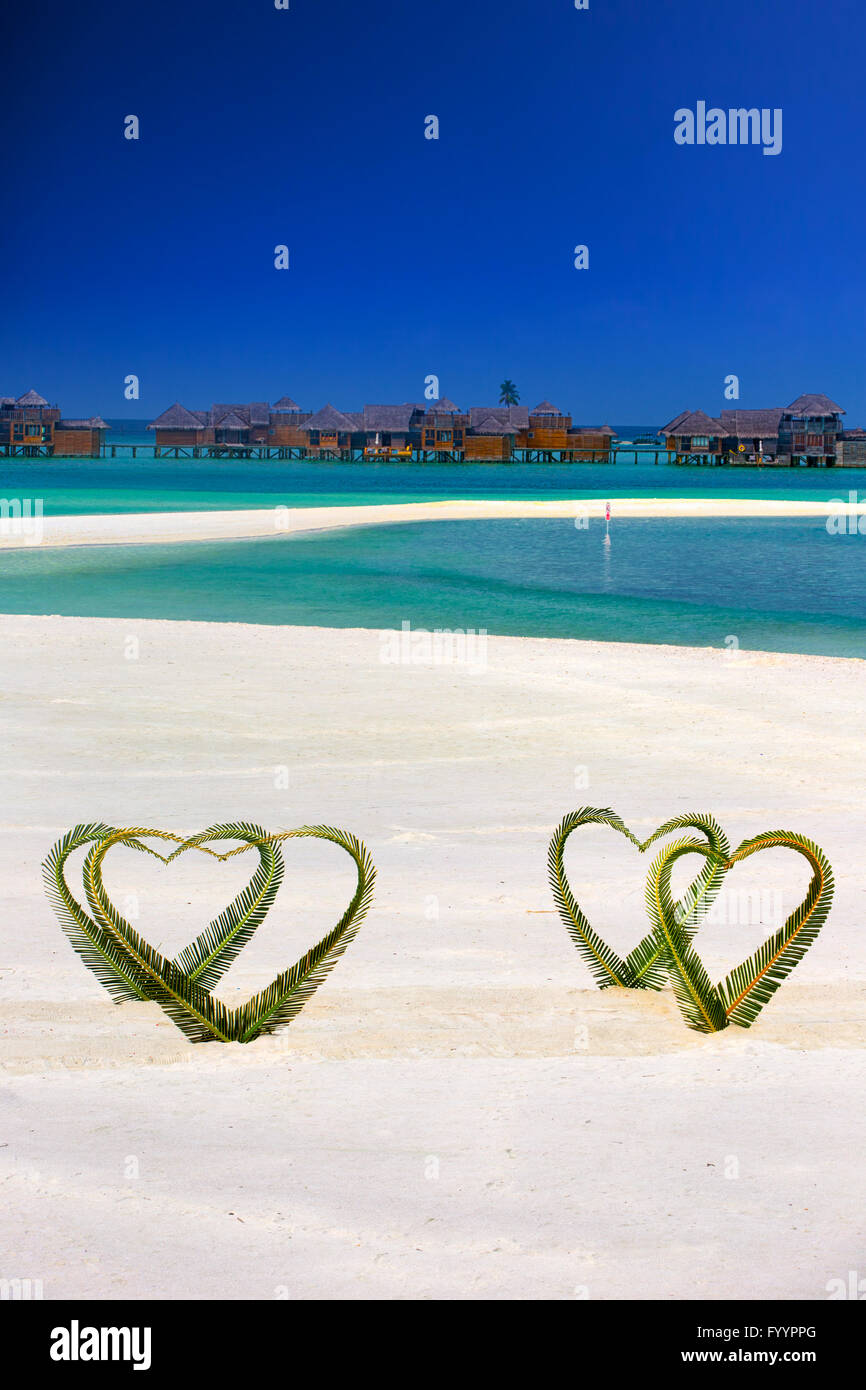 Herz der Palme Blätter auf tropische Insel mit Wasserbungalows im Hintergrund. Stockfoto