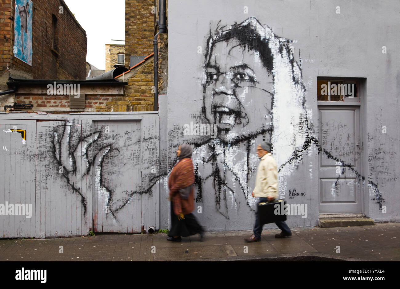 2 asiatischen Menschen vorbei gehen. street art auf eine Wand im Hanbury Street, London E1 Stockfoto