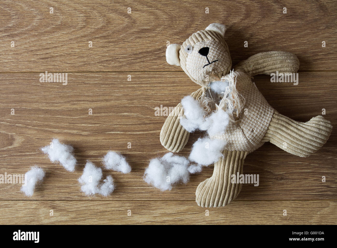 Eine traurige, verlassenen Teddybär mit seiner Füllung herausgezogen und in einem dunklen, hölzernen Fußboden verstreut. Stockfoto
