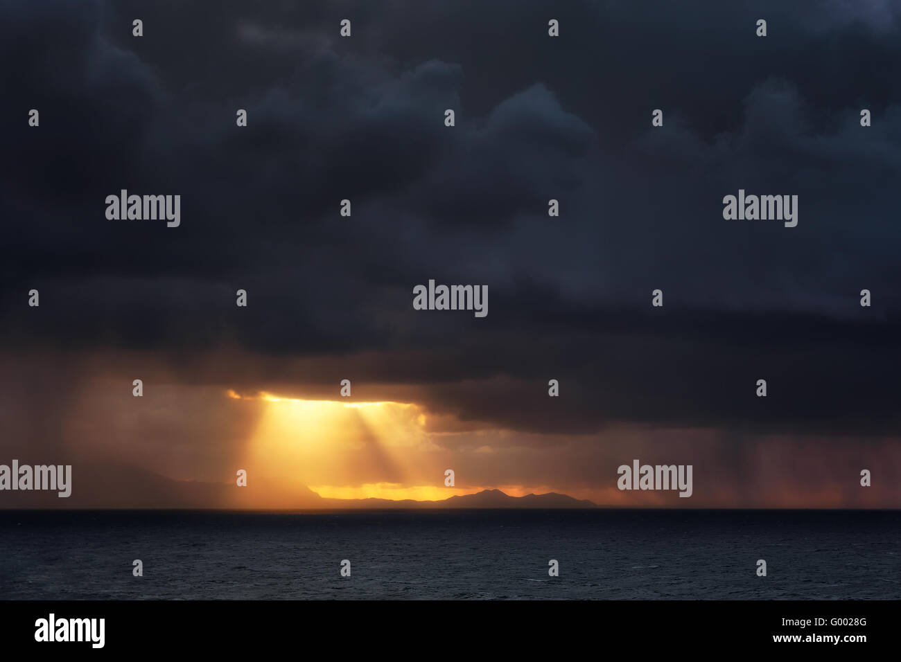 Regen und Sonne Strahlen am Meer bei Sonnenuntergang Stockfoto