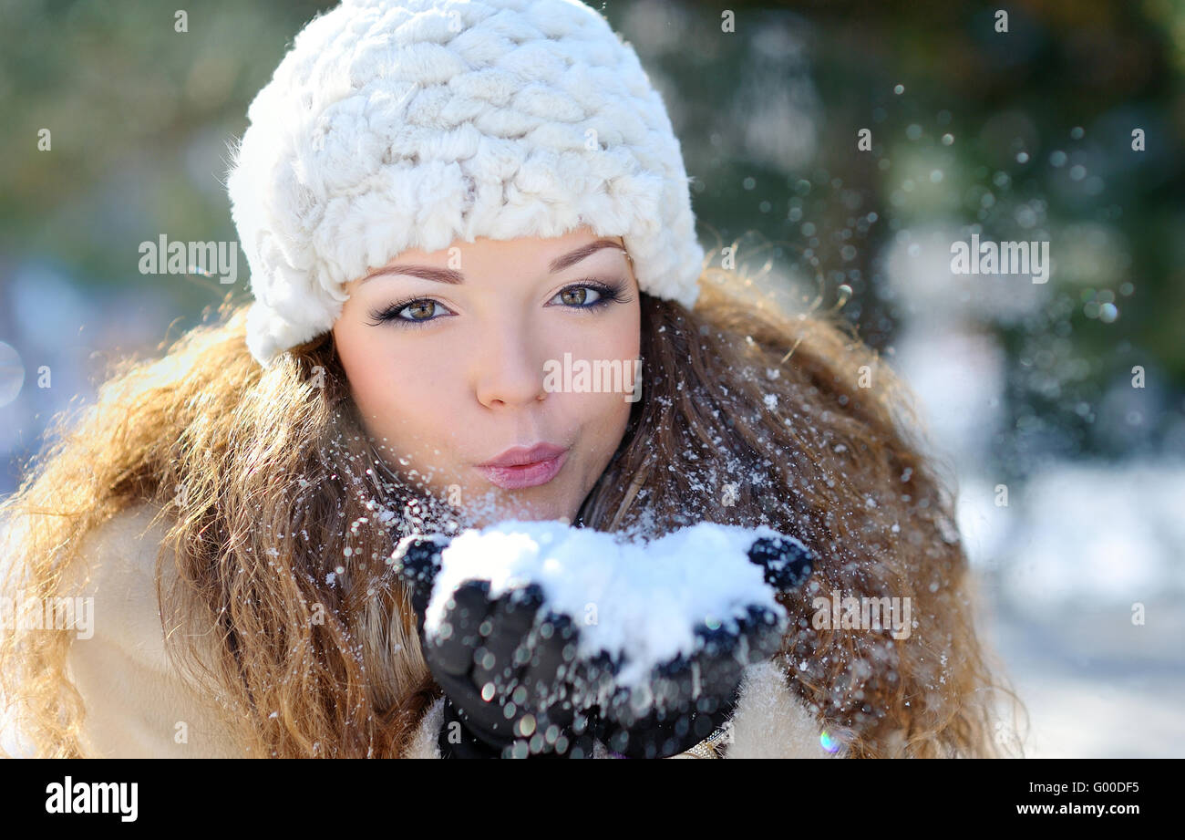 Mädchen tragen warme Winterkleidung und Hut wehenden Schnee im Winterwald Stockfoto