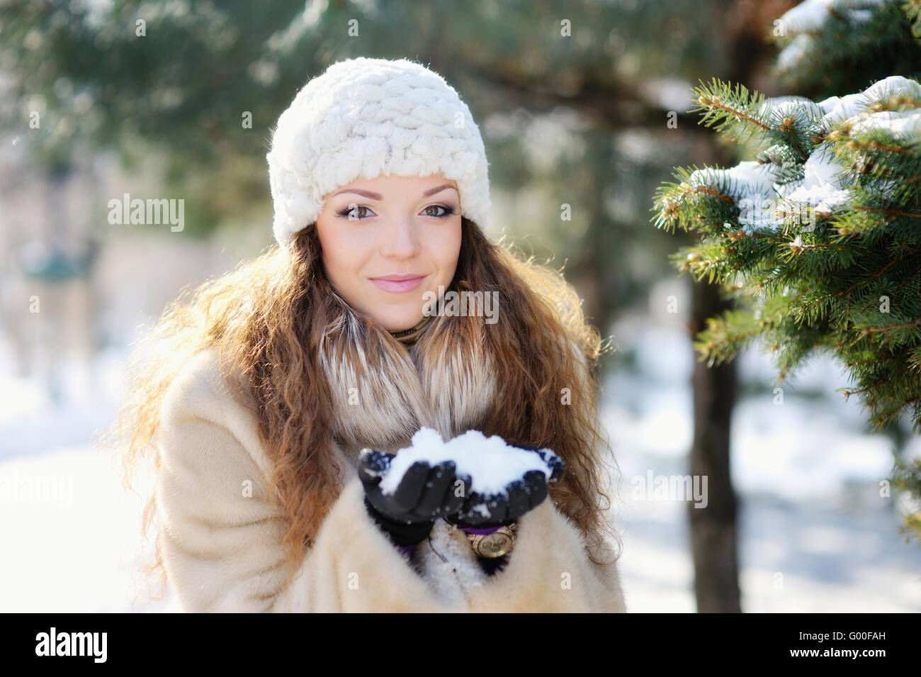Junge Frau in Hut und Handschuhe, lachen, spielen mit Schnee gro Stockfoto