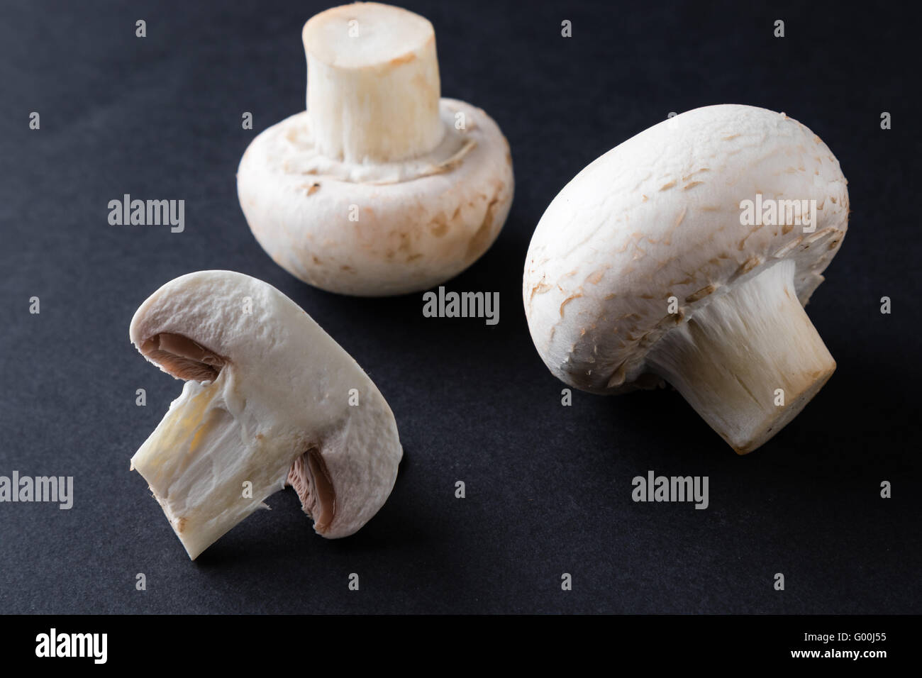 Champignon-Pilze auf schwarzen Tisch Stockfoto
