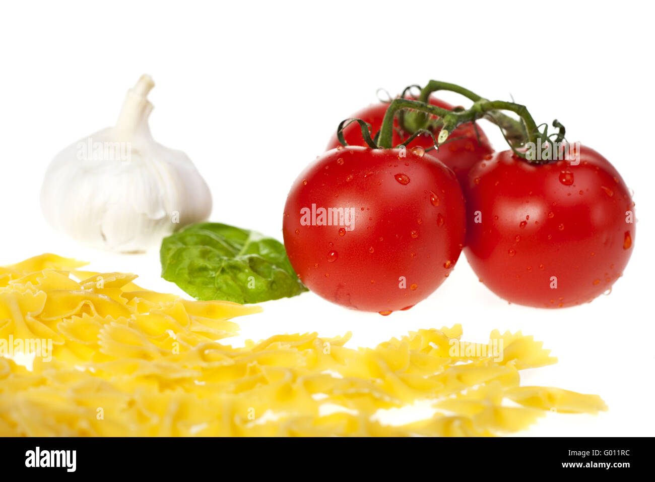 Farfalle Nudeln, Tomaten, Knoblauch und ein Blatt Basilikum Stockfoto