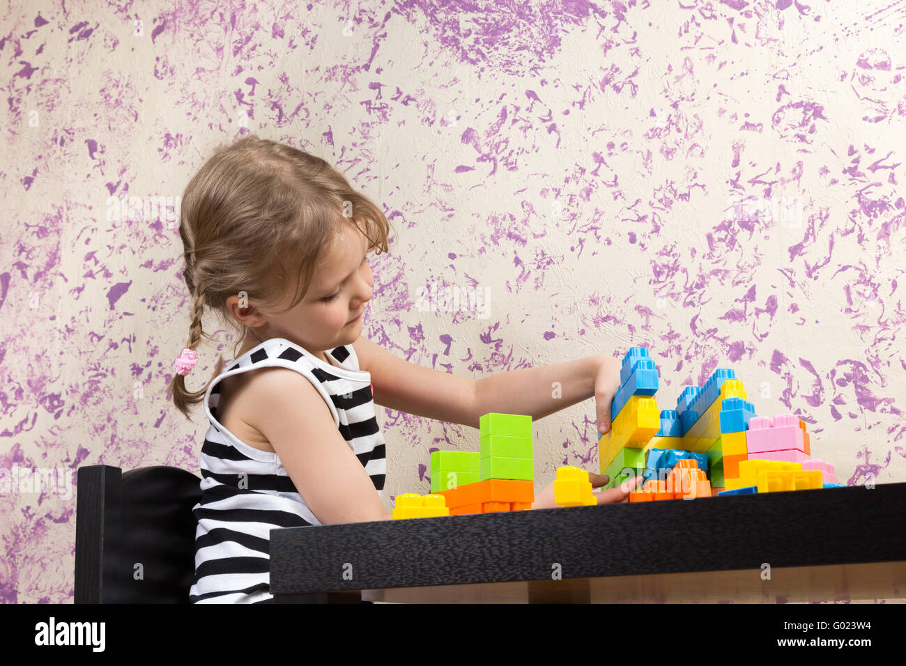 kleines Mädchen baut Ziegel am Tisch Stockfoto